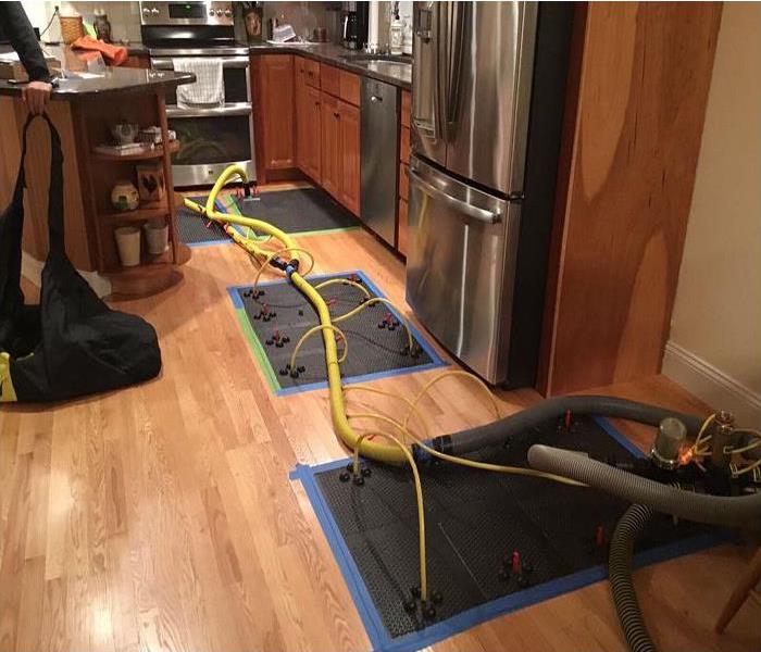 Floor mat drying system being used on wood plank flooring. Mats with water extraction hoses attached